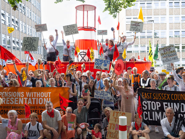 A large group of protestors in front of a model boat outside County Hall Lewes. They are demanding divestment from fossil fuel companies.